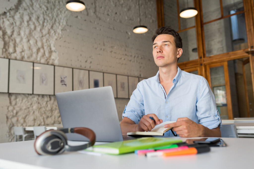 Male manager sitting at his desk, writing a performance plan document that outlines goals and support for his team instead of a formal performance review form.