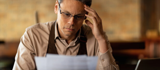 Stressed small business owner at desk struggling with holiday stress and year-end workload.