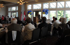 Rotary Club members and guests gathered at a community meeting, listening to a speaker and connecting in person