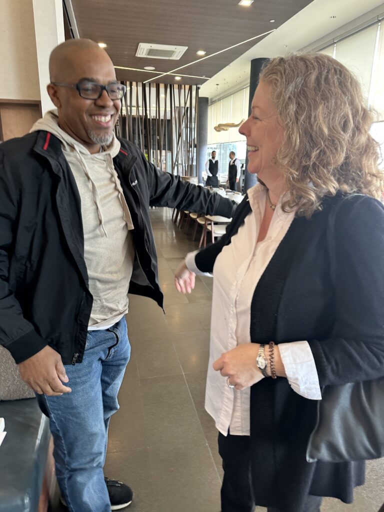 Certified Systems Business Coaches Anthony Gordon and Alison Minato greeting each other at an in-person gathering.