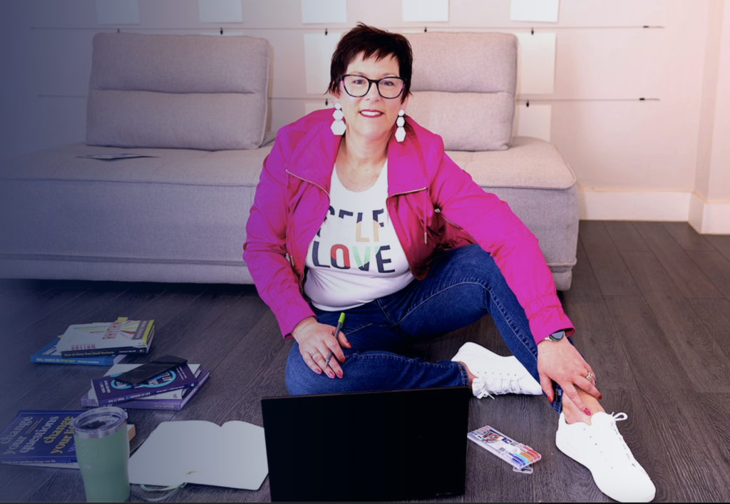 Kirsten Jenner, Certified Systems Business Coach, working with business planning materials and a laptop.